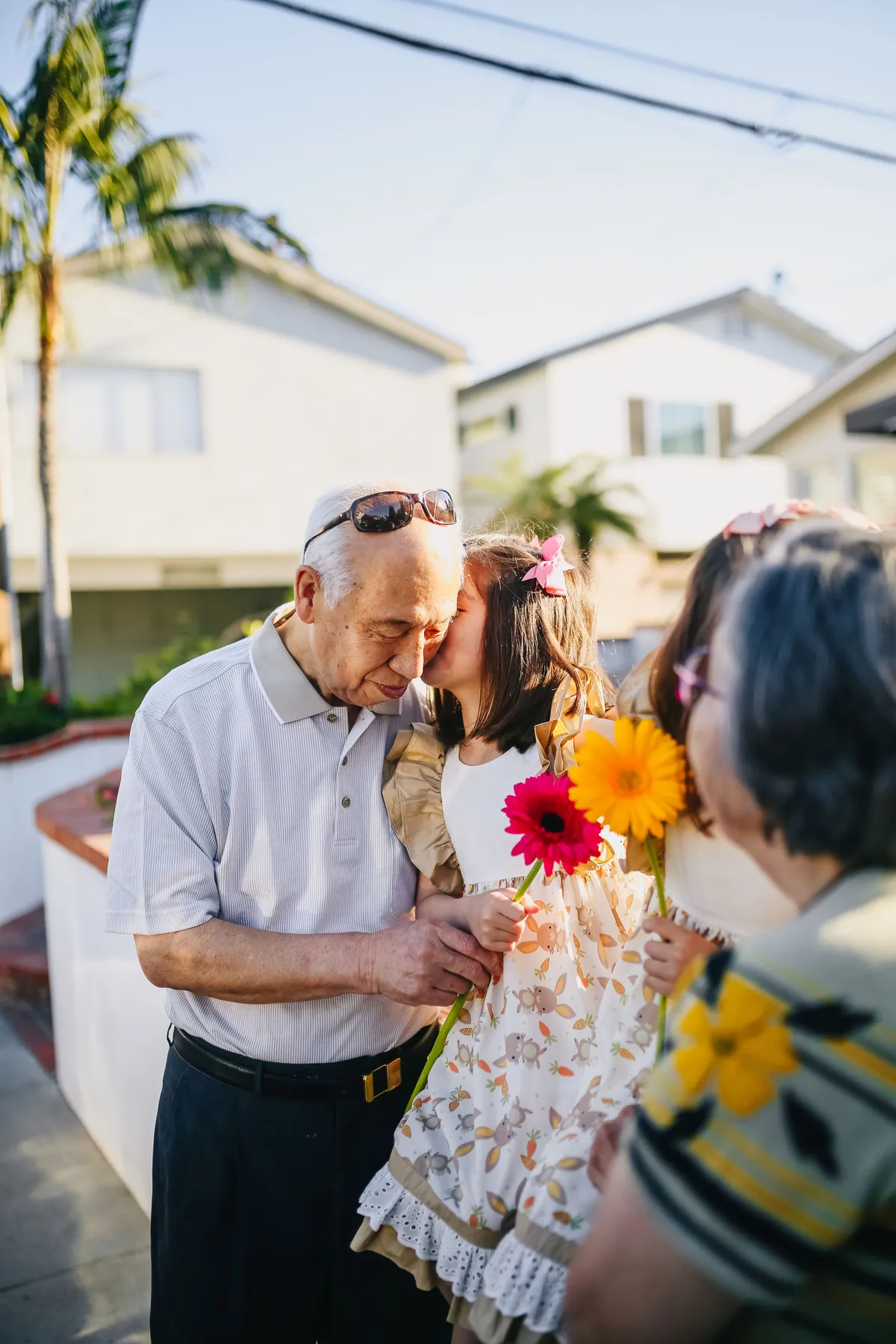 Older adults spending time outdoors with two children holding flowers.